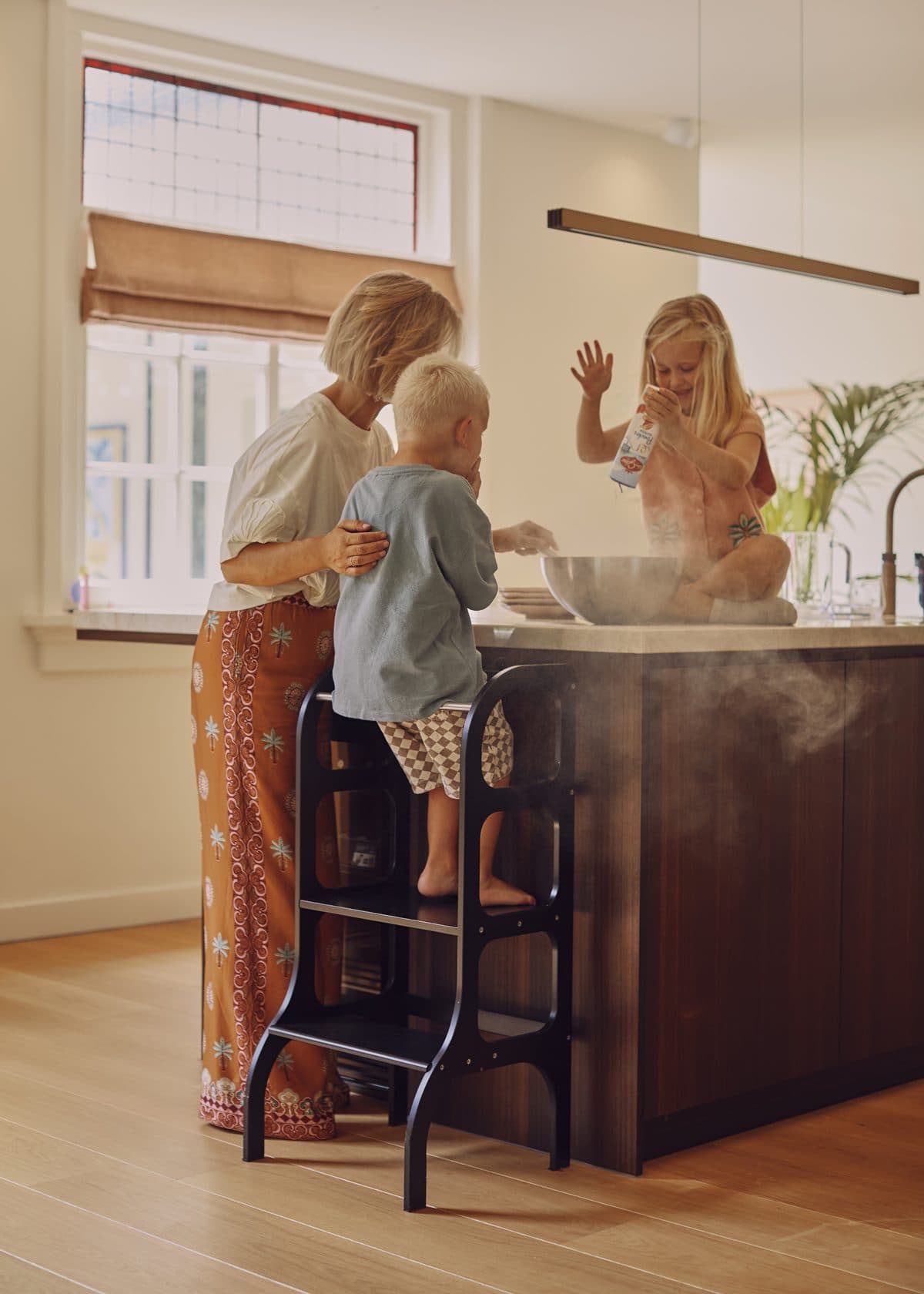 Moeder en kinderen bakken samen in de keuken op een lichte houten vloer