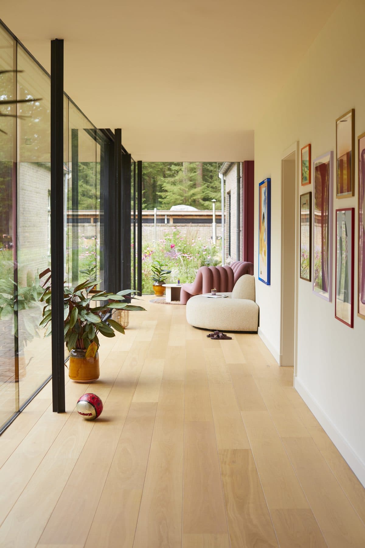 Woonkamer in een nieuwbouwwoning met een lichte eiken plankenvloer, crème bank en kunst aan de wand
