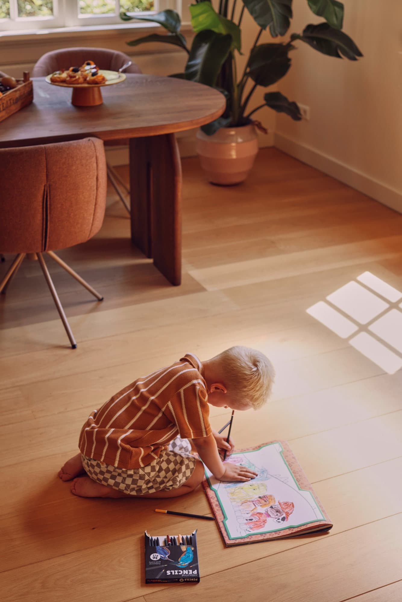 Kind tekent op een eiken vloer in de woonkamer